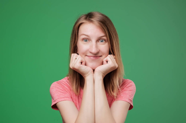 Усміхаючись європейських леді в рожевий футболку, дивлячись на камеру і посміхаючись, ізольовані на зеленому тлі. - Фото, зображення