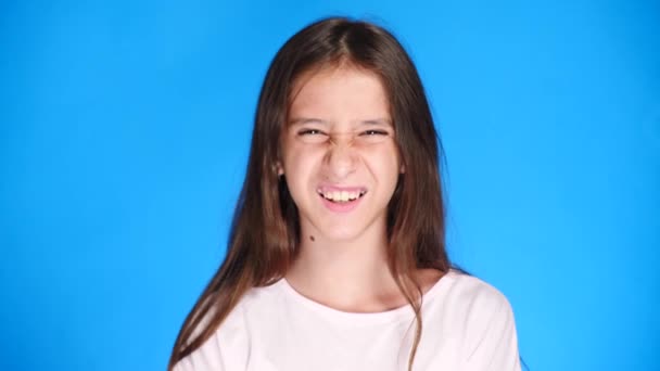 cute the girl teenager looks into the camera laughing and makes a funny facial expression. 4k, slow motion, close-up. color background - Filmagem, Vídeo