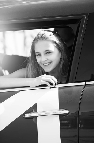 Happy pretty girl with pensive face looking through car window - Zdjęcie, obraz