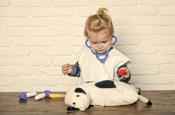Chłopiec gry lekarz z zabawka krowa na białej ścianie - Zdjęcie, obraz