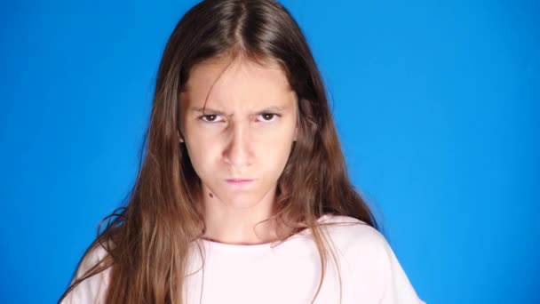 Close up. good looking sullen girl pouts lips, on blue background. Offended teen girl - Imágenes, Vídeo