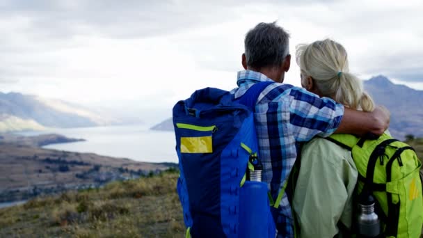 Szerető nyugdíjas kaukázusi pár a Iskolatáskák élvezi összetartozás trekking vadonban The Remarkables Otago Új-Zéland  - Felvétel, videó