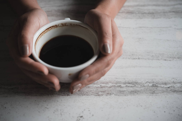 Vista dall'alto immagine delle mani di una donna che tiene una tazza di caffè sul tavolo nel caffè
 - Foto, immagini