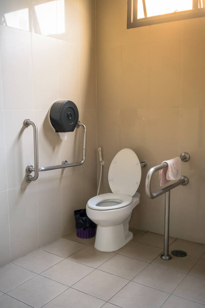 Interior do banheiro para idosos idosos com vaso sanitário e corrimão
 - Foto, Imagem