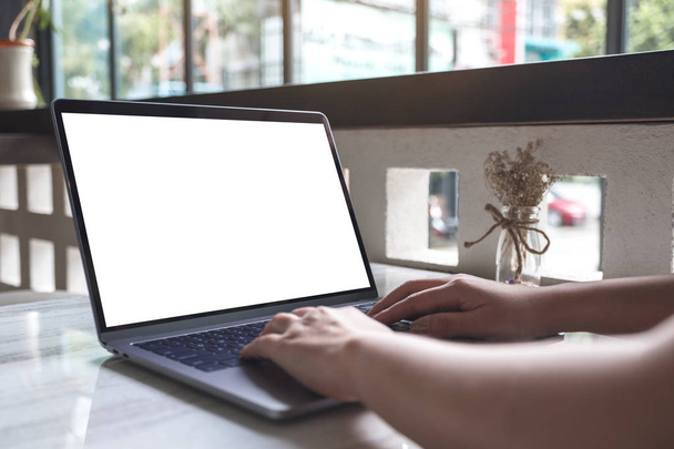 Κοντινή εικόνα μιας γυναίκας που εργάζεται και πληκτρολογεί σε πληκτρολόγιο laptop με φλιτζάνι καφέ στο τραπέζι - Φωτογραφία, εικόνα