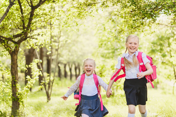 two funny school girls running holding hands outdoor - Fotografie, Obrázek