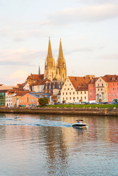 Regensburg şehir manzaralı, Almanya. İnsanlar kıyısında Danube Nehri, Regensburg Katedrali ve Stone Bridge arka planda, günbatımı güzellik keyfini çıkarın. - Fotoğraf, Görsel