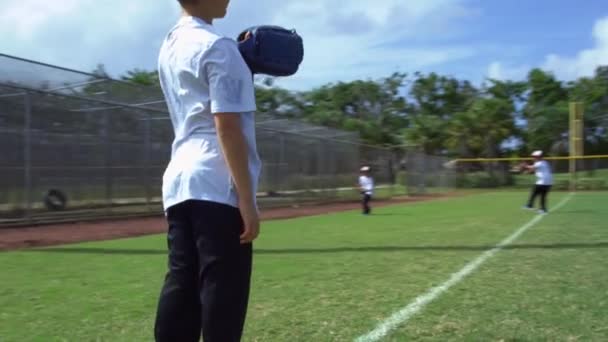 Movimiento lento de los niños lanzando pelota y la captura durante la práctica de béisbol en el parque
 - Metraje, vídeo