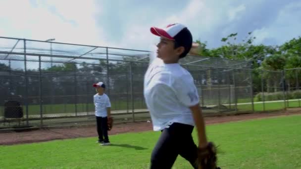 Gran toma de primer plano en cámara lenta de niños atrapando y lanzando pelota en el parque de béisbol durante la práctica
 - Metraje, vídeo