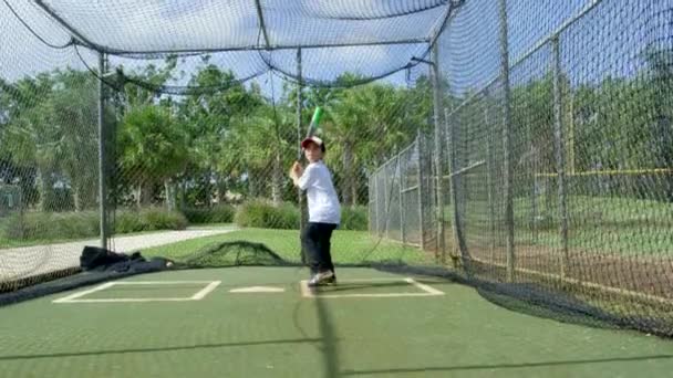 Медленный снимок ребенка в бейсбольной клетке в бейсбольном парке, ударяющего по мячу
 - Кадры, видео