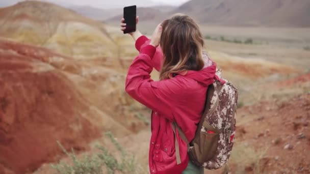 turista menina faz selfie no smartphone câmera. montanhas vermelhas e terra vermelha como em Marte
. - Filmagem, Vídeo