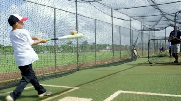 Movimiento lento del hombre y el niño practicando dentro de jaulas de bateo en el parque de béisbol
 - Metraje, vídeo