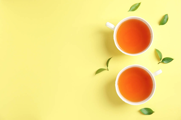 Flat lay composition with delicious tea and green leaves on color background - Valokuva, kuva