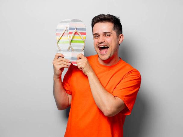 Young handsome man in orange t-shirt with sandals. Studio image on white background - Photo, Image