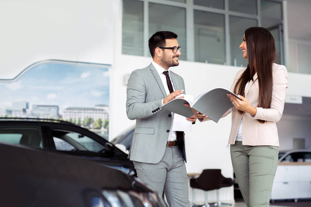 Professional salesperson selling cars at dealership to buyer - Foto, afbeelding
