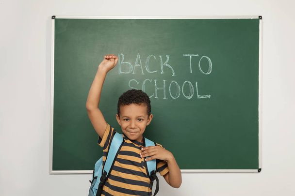 Little African-American child near chalkboard with text BACK TO SCHOOL - Valokuva, kuva