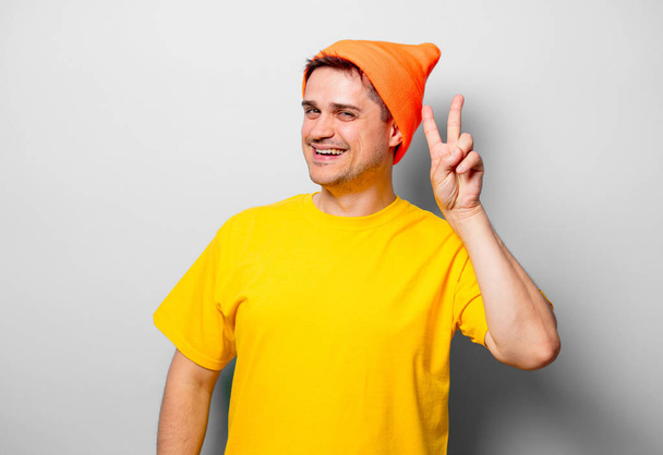 Jonge knappe man in geel t-shirt en oranje hoed op witte achtergrond - Foto, afbeelding