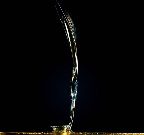 Close-up of oil and liquid pouring on dark background. - Φωτογραφία, εικόνα