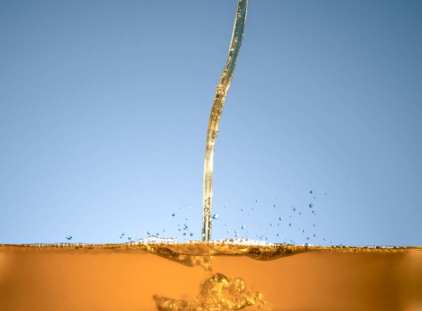 Close-up of oil and liquid pouring on dark background. - Foto, afbeelding