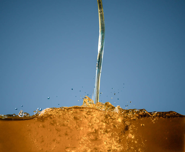 Close-up of oil and liquid pouring on dark background. - Foto, Imagen