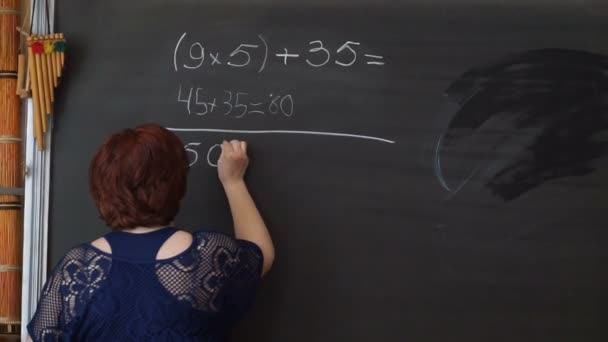 Teacher writing calculations on the blackboard in classroom - Footage, Video