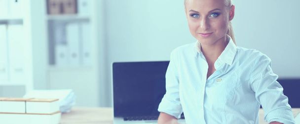 Attractive businesswoman sitting on a desk with laptop in the office - Foto, Bild