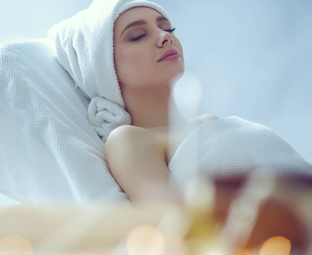 Young woman lying on a massage table,relaxing with eyes closed. Woman. Spa salon - Zdjęcie, obraz