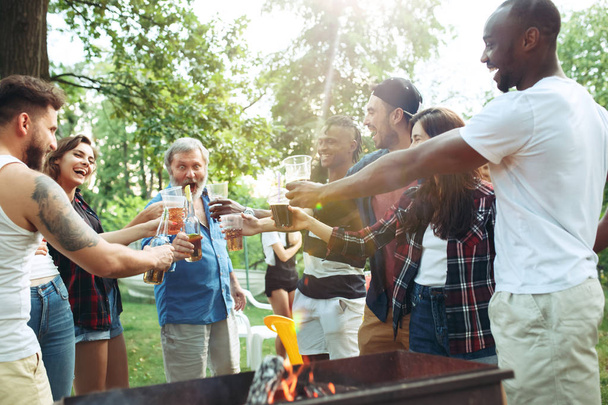 Group of friends making barbecue at the backyard. concept about good and positive emotions. Enjoying forest party with friends. Summer, party, adventure, youth, frienship concept - Photo, image