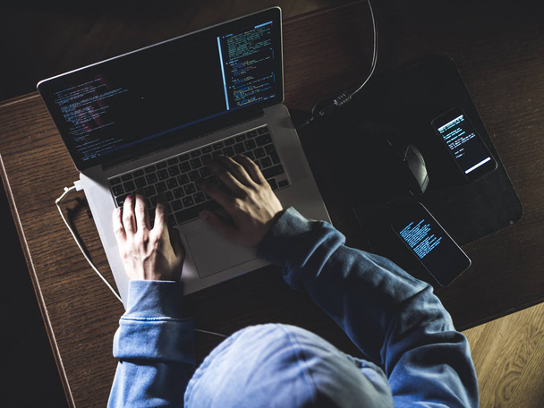 Overhead-Hacker in der Dunstabzugshaube arbeitet mit Laptop und Handy Texteingabe in dunklen Raum - Foto, Bild