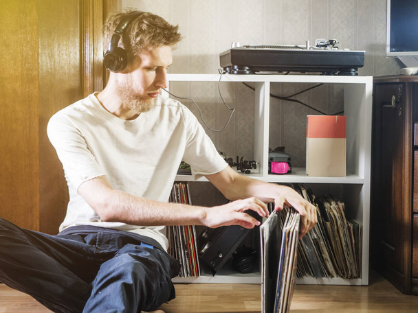 young man choose vinyl record to play next on turntable gramophone at home - Фото, зображення