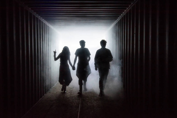Light at the end of the tunnel. Silhouette of friends in misty in underground corridor - Foto, immagini