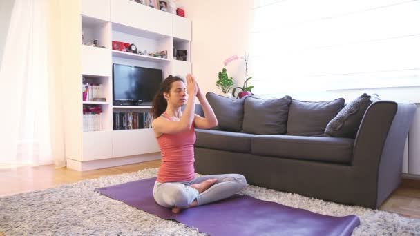 Молодая женщина медитирует, практикуя йогу, поза лотоса, ardha padmasana упражнения, расслабиться дома, здоровый образ жизни
 - Кадры, видео