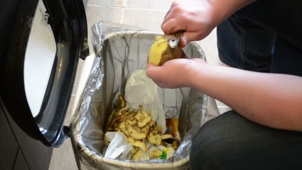 Las manos del hombre pelan patatas. Paring caer en cubo de residuos
 - Metraje, vídeo
