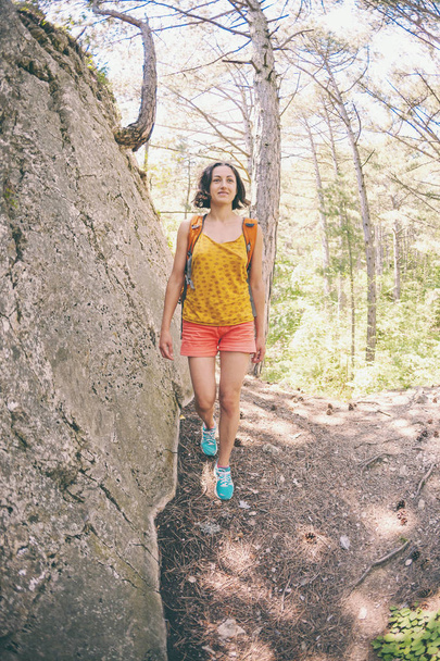 Het meisje loopt door het bos. Een jonge vrouw met een rugzak reist door de schilderachtige plaatsen. Een toeristische wandelingen langs een bergpad. Fisheye-lens. - Foto, afbeelding