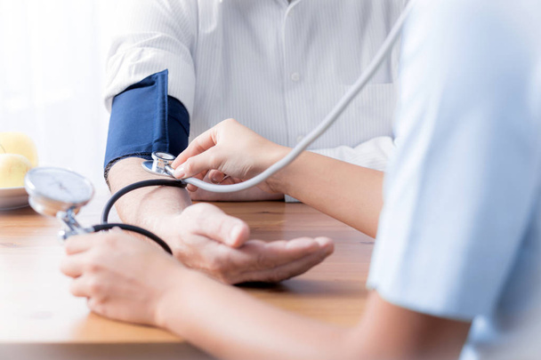 Close-up of nurse with stethoscope checking blood pressure of senior person - Photo, image
