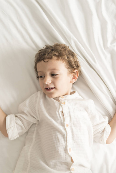 Child lying on the bed playing and gesturing. - Valokuva, kuva
