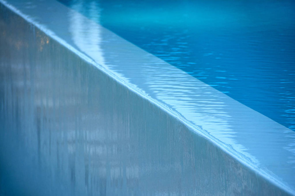 Абстрактна сцена з діагональним краєм басейну і потоком блакитної води вниз
 - Фото, зображення