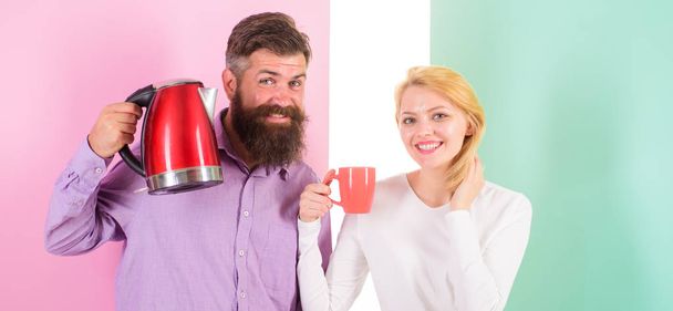 Spending good morning together. Modern devices make our life easier. Couple prepare morning drink electric kettle device. Electric kettle boils water very quickly. Prepare favourite drink in minutes - Photo, image