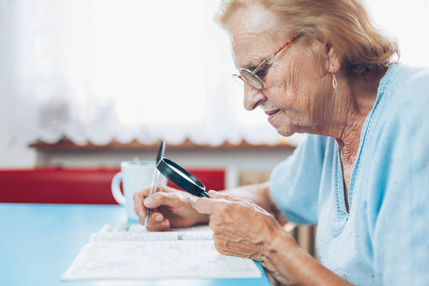 Senior woman in her 80s enjoys solving a crossword puzzle - Foto, Imagem
