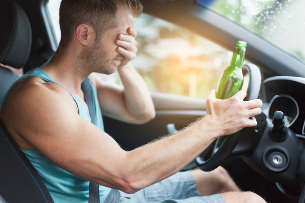 Drunk driver drinking behind the steering wheel of a car - 写真・画像