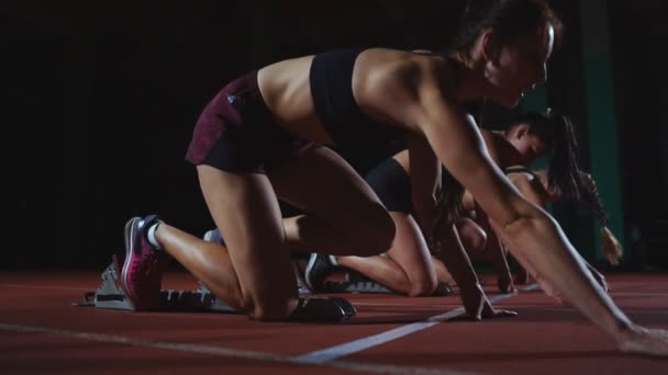 Läuferinnen auf der Leichtathletik-Bahn kauern vor einem Rennen in den Startlöchern. in Zeitlupe. - Filmmaterial, Video