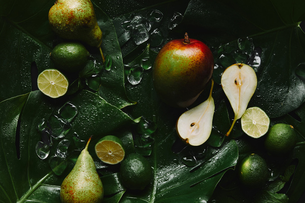 top view of fresh ripe fruits, ice cubes and beautiful green tropical leaves  - Fotoğraf, Görsel
