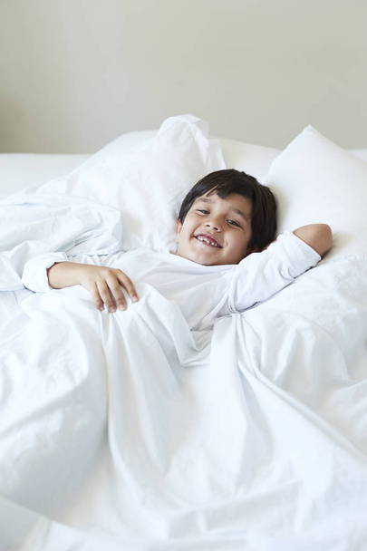 Smiling boy in bed, looking to camera - Foto, Imagem
