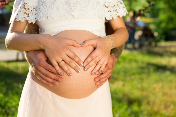 handen van een man en een vrouw op een zwangere buik - Foto, afbeelding