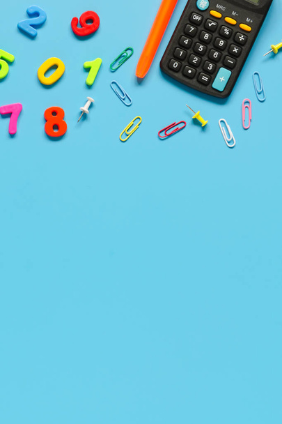 Calculator, pen, colorful numbers on blue background. Copy space composition - Fotografie, Obrázek