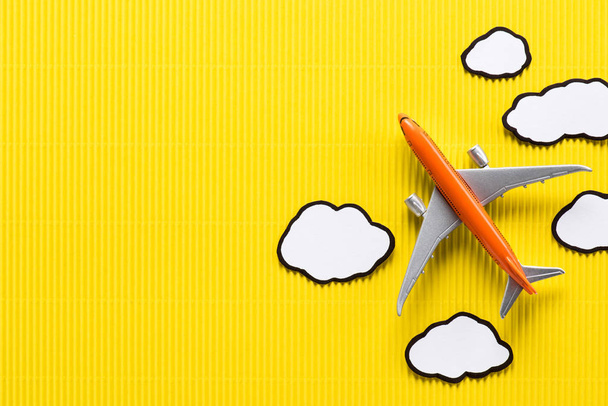 vista superior do avião de brinquedo e nuvens de papel no fundo amarelo, conceito de viagem
 - Foto, Imagem