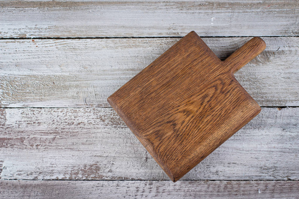 Cutting brown board on old shabby wooden background. Background with copy space, overhead, top view - Photo, Image