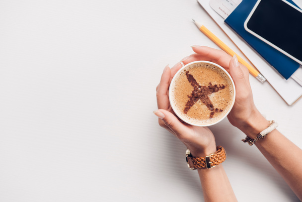 oříznuté záběr ženy držící šálek kávy s rovinou podepsat u stolu s pas, smartphone a letenky, cestování koncept - Fotografie, Obrázek