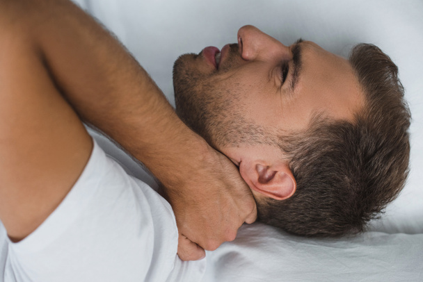 hombre acostado en la cama y sufriendo de dolor en el cuello
 - Foto, Imagen