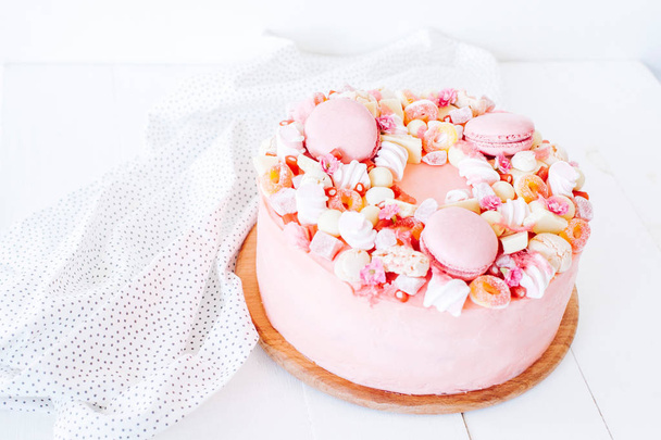 Vaaleanpunainen kakku Koristelu makeisista, makaroneista, vaahtokarkeista, valkoisesta suklaasta. Kiva syntymäpäivälahja. Tytölle
. - Valokuva, kuva